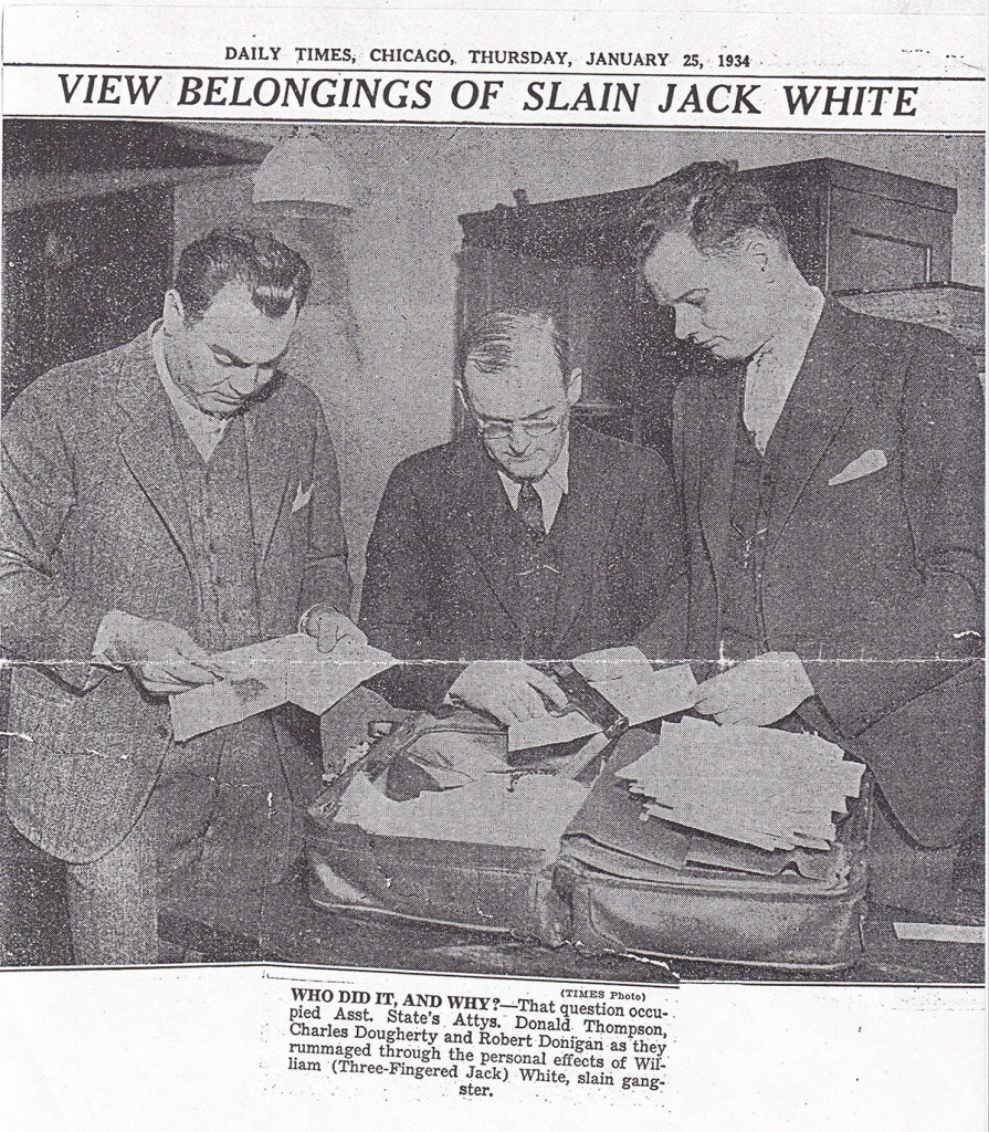 Men examining documents on table, 1934 newspaper.