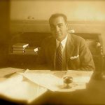 A sepia image of a man at his desk